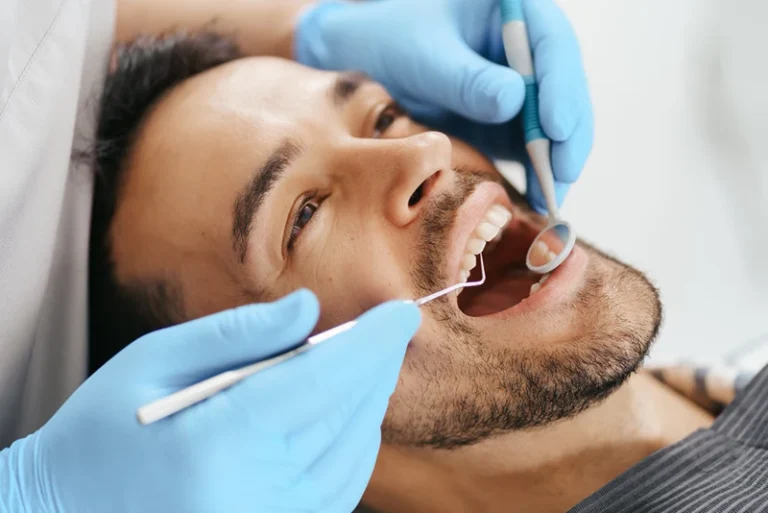 Dentista explorando el estado de las encías de un paciente para valorar un curetaje dental en Hospitalet