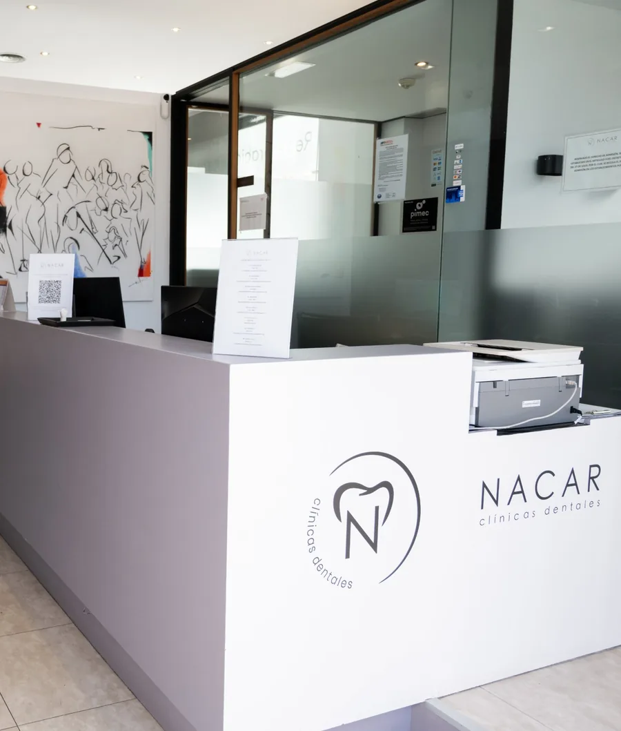 Recepción de Clínica Dental Nàcar en L’Hospitalet de Llobregat, con el mostrador y el logotipo de la clínica