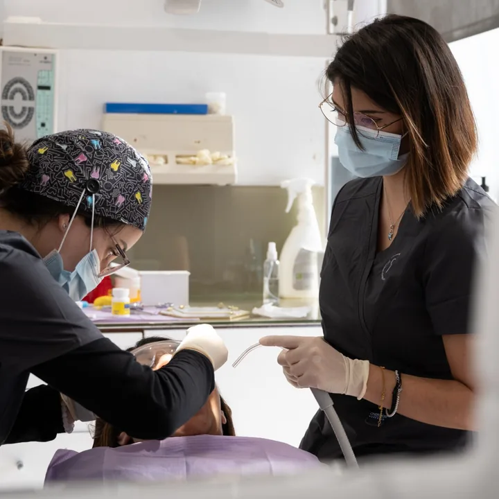 Dos dentistas de Clínica Dental Nàcar atendiendo a una paciente en el gabinete